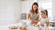 © Vyatcheslav - Mother and daughter decorating cupcakes for Easter in a bright kitchen. Happy family baking together. Woman and child with bunny ears preparing spring treats