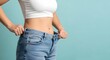 © Vicentia - woman shows off her significant weight loss by wearing old jeans that are now too big for her slim waist. A visual representation of a successful fitness journey and health goals achieved