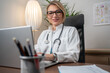 © Nenad - Joyful female doctor using notebook in clinic