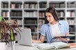 © BillionPhotos.com - Student typing on laptop, studying in library