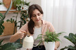 © New Africa - Woman watering beautiful potted houseplant at home