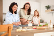 © Pixel-Shot - Happy little girl, her pregnant mother and granny filling cookies with fruit jam in kitchen