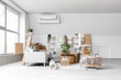 © Pixel-Shot - Grey sofa, coffee table and cardboard boxes in light living room on moving day