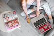 © Pixel-Shot - Woman with credit card and makeup products shopping online on sofa at home, top view