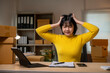 © Wasana - Stressed asian businesswoman holding her head with her hands at her desk