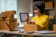 © Wasana - Young entrepreneur preparing packages for shipment at her home office
