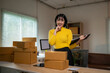 © Wasana - Asian female entrepreneur managing inventory and planning shipments in her startup office