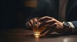 © hatma - Close up of a man’s hand holding a glass of whiskey on a wooden table with dark, elegant lighting. Concept of luxury, nightlife, alcohol, relaxation, business, and modern bar atmosphere.