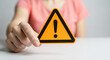 © Mobasser - A woman holding a warning sign with an exclamation mark in her hand