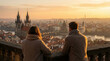 © Video80X - A couple in warm clothing stands on a balcony overlooking a historic European city at sunset, ideal for travel themes.