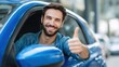 © LimeSky - Joyful young man giving a thumbs up from the window of a blue car in a parking lot pleased with his new vehicle