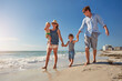 © BuyoutReese07/peopleimages.com - Walk, holding hands and love with family at beach for summer vacation, bonding and support. Connection, tropical holiday and weekend break with parents and children outdoor for travel and trust