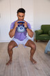 © wavebreak3 - Man with 8 kg kettlebell close to chest while squatting in living room workout area