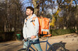 © Oscar - Courier delivering food by bicycle in urban park