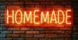 © antishock - Bright neon sign spells homemade against textured brick wall. Warm lighting creates inviting atmosphere. Simple, bold design.