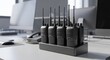 © Farhan - Row of professional handheld radios in a charging base on a white corporate workplace desk