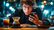 © StasySin - Young man in formal attire sits at a table, holding a smartphone, with a glass of coffee and an open notebook in front, surrounded by soft bokeh lighting