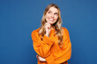 © ViDi Studio - Young happy fun Caucasian woman she wear yellow sweater casual clothes put hand prop up on chin, lost in thought and conjectures isolated on plain blue background studio portrait. Lifestyle concept.