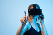 © Volodymyr_sh - Female user interacting with virtual interface using VR headset, finger pointing gesture and immersive technology concept
