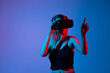 © Volodymyr_sh - Woman adjusting virtual reality headset in studio with blue and red light, immersive digital exploration concept