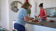 © Marco - Two women prepare breakfast together in modern kitchen, cutting bread and gathering ingredients with fruit and utensils on counter