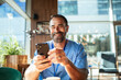© Marko Geber - Smiling healthcare worker using smartphone during coffee break in cafe