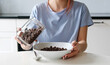 © Ievgen Skrypko - Girl Pouring Brown Cereal Balls Into A Plate For Breakfast