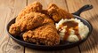 © Yearun - Golden, crispy fried chicken pieces are abundantly piled in a rustic cast iron skillet, accompanied by a generous dollop of creamy mashed potatoes drizzled with rich brown gravy.