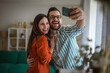 © Miljan Živković - Happy couple taking selfie at home enjoying togetherness