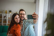 © Miljan Živković - Happy couple taking selfie at home enjoying togetherness