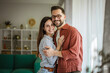 © Miljan Živković - Happy couple embracing, smiling, standing in home