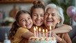 © Mike Ebony - A happy family of three generations smiling together with a birthday cake