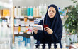 © JackF - Young Muslim woman scans a package of pills with a mobile barcode against the background of shelves in a pharmacy. Buyer pays for purchases by QR