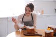 © New Africa - Young woman decorating traditional Easter cake with glaze in kitchen