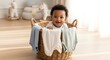 © ArtSync Studio - Cute Baby with Afro Sitting in Basket Full of Clothes Smiling