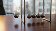 © Running opossum - newton's cradle swinging in a modern office setting with sunlight reflecting on metal balls