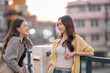 © Apichat - Two asian women enjoying conversation in city at sunset