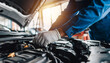 © justsann - Mechanic working on car engine in auto repair shop.