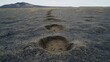 © NurStock - Deep muddy footprints impressed into loamy soil creating a path across barren terrain