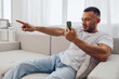 © SHOTPRIME STUDIO - Engaged man interacting with smartphone, showcasing enthusiasm and connection in a cozy, modern living space. Perfect for illustrating digital communication trends.