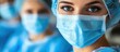© adiba - Surgeon's intense gaze, masked team in background, hospital setting, medical stock photo