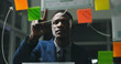 © Azeemud25/peopleimages.com - Glass wall, night or black man in office with review, strategy or planning for report. Problem solving, sticky note or employee with insight, idea board or brainstorming deadline on evening shift.