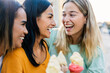 © Xavier Lorenzo - Multiracial female friends enjoying ice cream outdoors. Young women sharing laughter and sweet moments during summer travel. Friendship and vacation concept.