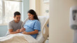 © Таня Андреева - Pregnant Hispanic woman in blue gown and partner touching belly in bright hospital room.