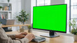 © IRON - Modern office workspace with person typing at desk and green screen monitor for customizable digital contentv
