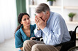 © Prostock-studio - A woman with dark hair listens to a man with gray hair as he expresses his feelings while seated in a wheelchair. They are in a well-lit room with plants in the background.