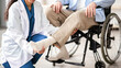 © Prostock-studio - A healthcare worker is assisting a man using a wheelchair with foot care in a clinic. The worker is examining the man's legs while providing support and care.