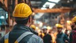 © Maryna - A man in a yellow hard hat stands in front of a group of people