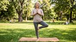 © Gab - Senior woman practicing yoga tree pose outdoors in sunny park, mindfulness meditation, healthy aging and relaxation concept, lifestyle fitness and balance exercise in nature
