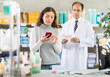 © JackF - Male pharmacist in medical uniform helps customer in casual clothes find baby formula from photo on the Internet.